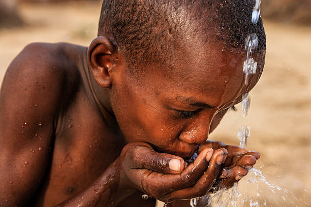 African young boy from Samburu tribe drinking fresh water on savanna.  Potable water is very precious in Africa - women and children often walk long distances through the savanna to bring back jugs of water that they carry on their back.